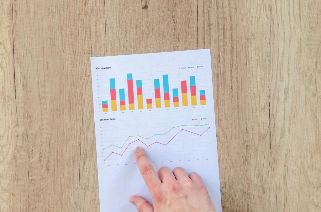 A  person pointing to two sets of charts on a printed page.